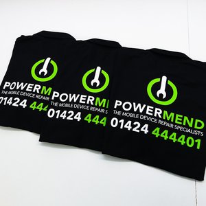 Photo of black polo shirts with PowerMend electronics repair shop branding in white and apple green colours